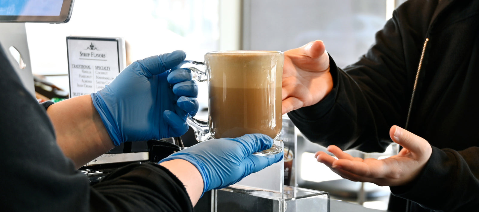 Dilettante Chocolates woman handing customer a tall coffee