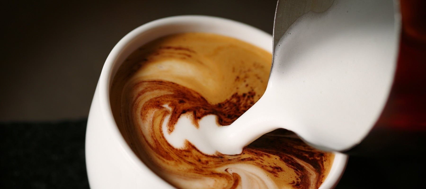 Milk being poured into a mocha or latte drink